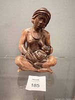 Front view of the mother and child wooden sculpture held by the seated woman, showing full figure and child in lap.
