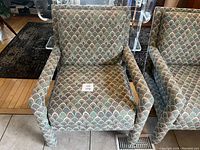 Front view of Parsons style chair with distinctive scalloped multicolor upholstery and squared armrests.