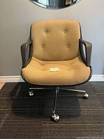 Front view of vintage postmodern swivel office chair showing button-tufted yellow upholstery, black molded armrests, and metal caster base.