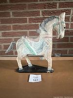 Front view of the vintage wooden horse figurine with visible painted and carved details on brick background.