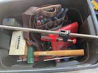 Top view of bin showing assorted screwdrivers, green mallet, wooden-handled hammer, leather pouch, and Tekton wooden box.