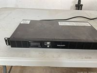 Front view of the CyberPower backup power supply unit showing front panel with LCD, power button, and ventilation grills.