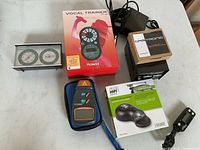 Overview of all items on white table including gauge, tuner box, tachometer, stylus cleaner, transformer, foot switch, remote