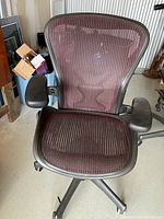 Front view showing red mesh seat and back, adjustable armrests, five-star base