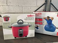 Photo showing boxed Salton automatic rice cooker and GoodLife Fitness exercise ball against a cinder block wall with metal garage door tracks