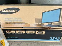 Boxed Samsung SyncMaster 2343 23-inch LCD monitor showing brand, model, and features including 2048x1152 resolution, 5ms response time, 50000:1 dynamic contrast ratio, and low power consumption