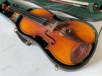 Skylark violin in case showing front body, bridge, strings, chin rest and bow horsehair tangled.