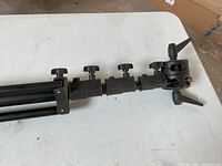 Close-up of the tripod stand's adjustment knobs and mounting head with tightening screws to show mechanism details and condition.