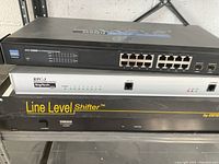 Stack of four electronic devices showing front panels: Linksys switches, BayTech RPC-3 power control, Yamaha DA3100 line level shifter.