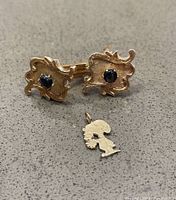 Overhead view of both cufflinks and Snoopy charm displayed on gray surface