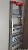 Full view of folded 6ft aluminum Werner A-frame ladder with red top handle and multiple steps visible.