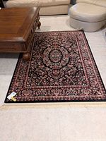 Full view of rectangular area rug on tiled floor, showing intricate floral pattern and fringe edges.