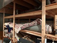 Rolled rug and pad stored on wooden shelves in basement