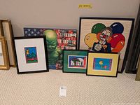 Full view of five framed artworks including stitched clown, Baby Hulk canvas, and three smaller prints