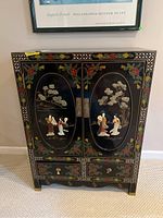Front view of closed cabinet showing two painted doors with applied figures and floral border