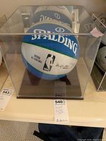 Full view of the Spalding blue and white NBA official All-Star basketball in clear display case on white shelf, showing overall item.