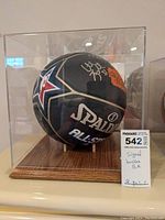 Front view of signed black Spalding NBA All-Star basketball in acrylic display case with wooden base