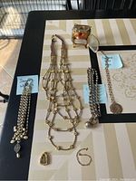 Seven costume jewelry pieces arranged on a table, showing overview of lot and identifying note papers for brands Seasonal Whispers and Catherine Lance Pesco.