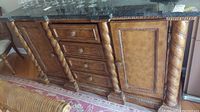 Front view of heavy wood credenza with granite-type top showing four drawers and two doors with twisted column details and round knobs.