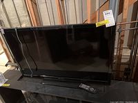 Full front view of the Emerson 39-inch TV on a stand with power cable and remote control in front.