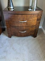Front view of the nightstand showing two drawers with silver handles and wood grain finish.