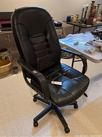 Full view of black office chair showing padded back and seat, armrests, and rolling wheels base.