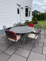 Outdoor patio with round wrought iron table and six matching chairs on paved patio