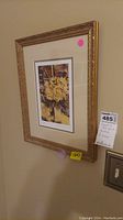 Gold framed floral print signed and numbered, hanging on a wall with label and tag visible