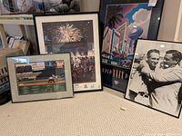 Four framed sports posters arranged on carpet: baseball, football, signed hockey print. Shows different sizes and subjects.