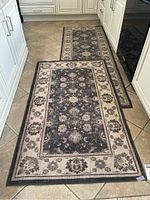 Two Ruggable washable rugs placed on tile floor with floral border pattern, 3x5 ft smaller rug in front and 7x2.5 ft runner behind it.