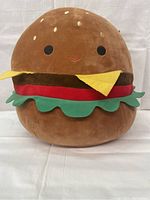 Front view of Carl cheeseburger Squishmallow plush showing facial features and detailed bun