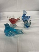 Lot of 4 art glass bird figurines displayed on white background showing colors and shapes