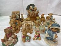 Group view of 16 Cherished Teddies figurines arranged on a white cloth background showing various teddy bear characters and some small animal figurines.