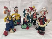 Front view showing all five colorful clown figurines arranged in a row on a white surface.