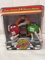 Front view of the M&M Rock'n Roll Cafe dispenser in original packaging showing the red and green M&M characters and jukebox.