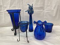 Photo showing full set of five cobalt blue glass items including various candle holders and vases.