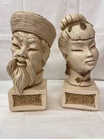 Front view of male and female vintage chalkware busts on square bases with textured panels