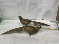Two brass pheasant bird figurines side by side, one with broken feet.