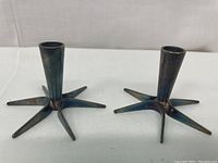 Pair of mid-century modern metal star-shaped candle holders showing the patina on the metal and star-shaped base with six arms.
