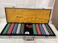 Full view of poker chips set in a metal carrying case with cushioned yellow interior lining, including chips in multiple colors and accessories.