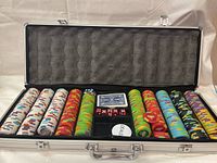 Open poker set case showing multiple stacks of poker chips, two decks of cards, dice, and dealer button inside