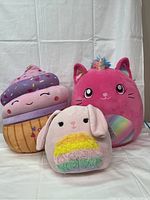 Front view of three Squishmallows plush toys, cupcake, unicorn cat and bunny, showing colors and designs.