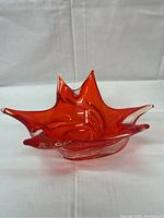 Front angle view of orange and clear glass bowl with six finger points and swirl design.