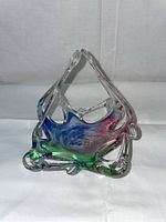 Front angled view of vintage Murano glass basket with blue, pink, and green swirls and organic shaped clear glass handles.