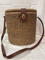 Closed vintage wicker picnic basket showing exterior with leather strap and clasp