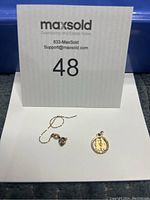 Photo of small gold chain segment and 10K gold Dutch girl and boy charm together on a white background.