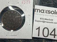 Close-up photo of one side of the 1888 Canadian one cent penny coin showing the denomination and date inside a decorative border, displayed in a square cardboard holder with clear plastic window.