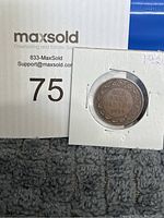 Photo shows Canadian one cent coin from 1920 inside protective flip holder with leaf and vine detailing around the text.