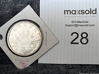 Reverse side of 1966 Canadian silver dollar showing canoe design with two figures and trees.