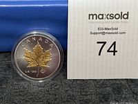 Photo of the front side of the 2020 Canadian coin showing a gold-toned maple leaf design with 'CANADA' labeled on top and 'L.E. 1000' and a small maple leaf symbol below.